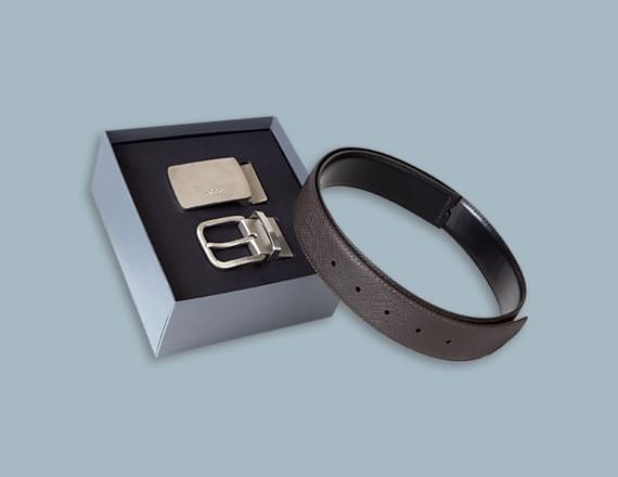 A black and silver belt with a silver buckle displayed inside an elegant gift box.