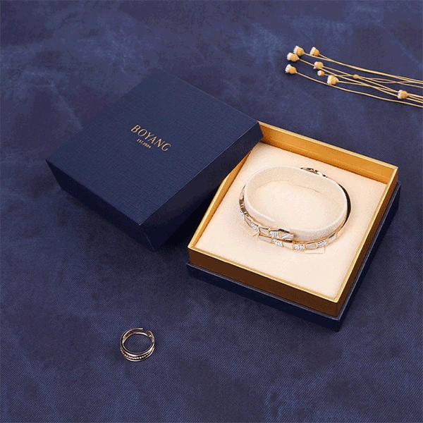 A blue box containing a gold chain and a gold bracelet, elegantly displayed for presentation.