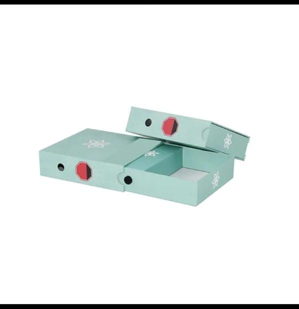 A pair of green boxes featuring prominent red buttons on their front surfaces.