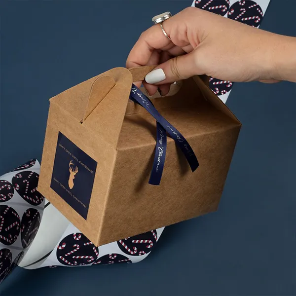 A woman holds a gift box tied with a ribbon, smiling as she prepares to present it.