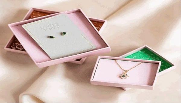 A pink box containing a necklace and matching earrings, elegantly displayed for presentation.