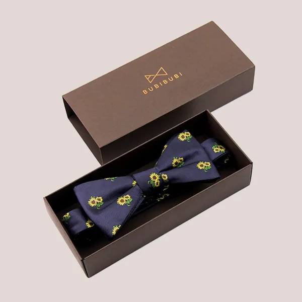 A bow tie displayed in a brown box featuring a vibrant yellow and blue pattern.